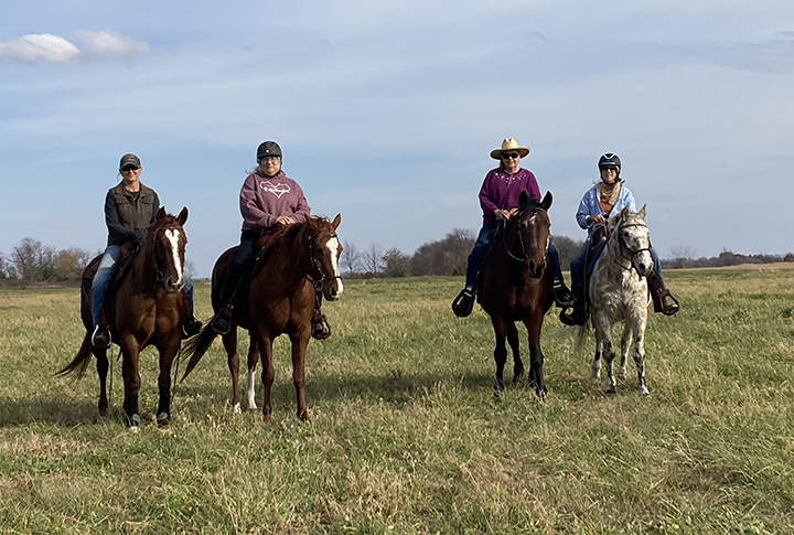 four riders on horses approach the Silverwood parking lot from the east